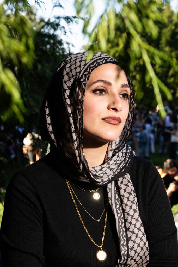 A woman in a hijab poses by a tree